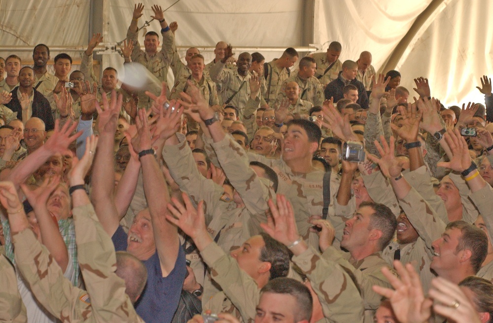 Service members reach for an autographed football thrown by Elwa