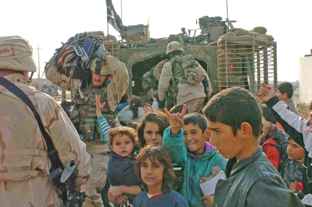 Soldiers hand out backpacks to rural Iraqi children