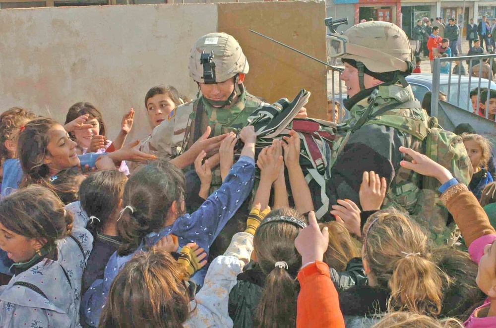 Soldiers hand out backpacks to rural Iraqi schoolchildren