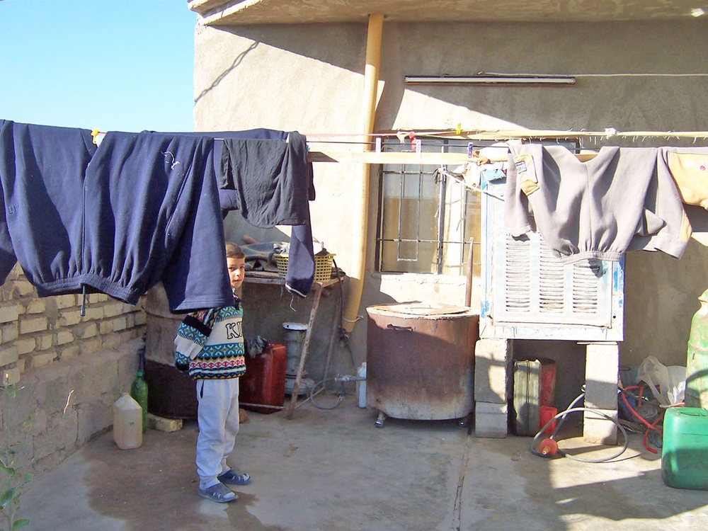 An Iraqi boy stands next to a newly replaced window