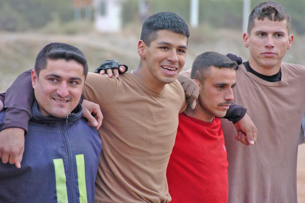 John Salas smiles for a photo with some Iraqi Police soccer play