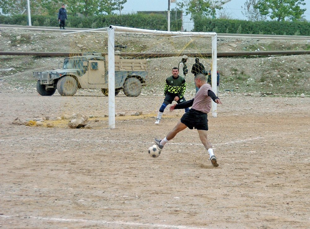 William Reynoso kicks a soccer ball toward the Iraqi Police goal