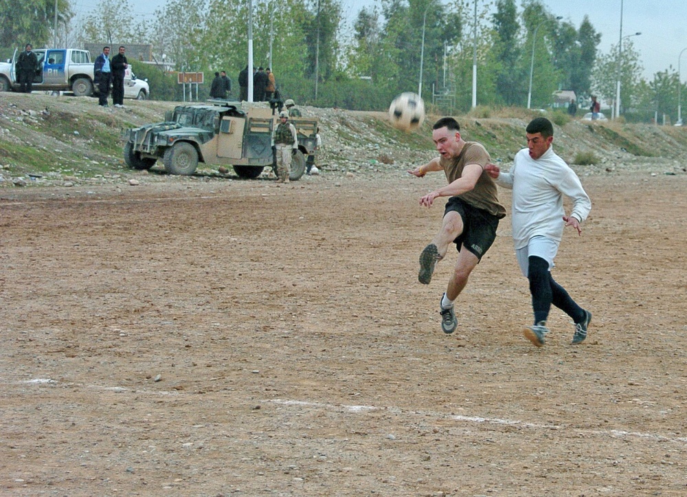 Elliot Scott kicks a soccer ball toward the Iraqi Police goal