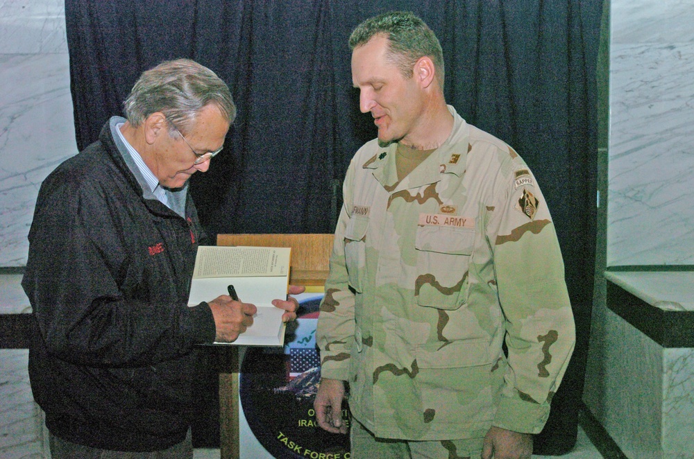 Secretary Rumsfeld signs book for Soldier in Iraq