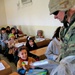 A Soldier hands a packet of school supplies