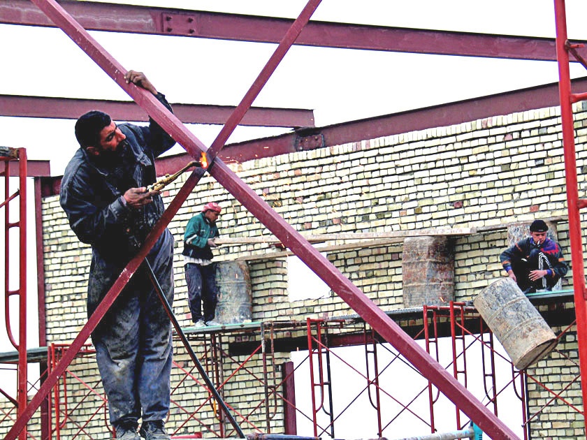 A local man welds a frame that will support the roof