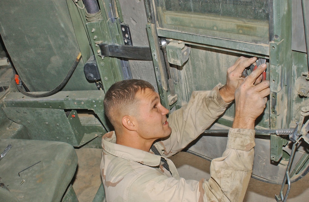 Sgt. Coco repairs the door of an up-armored HMMWV