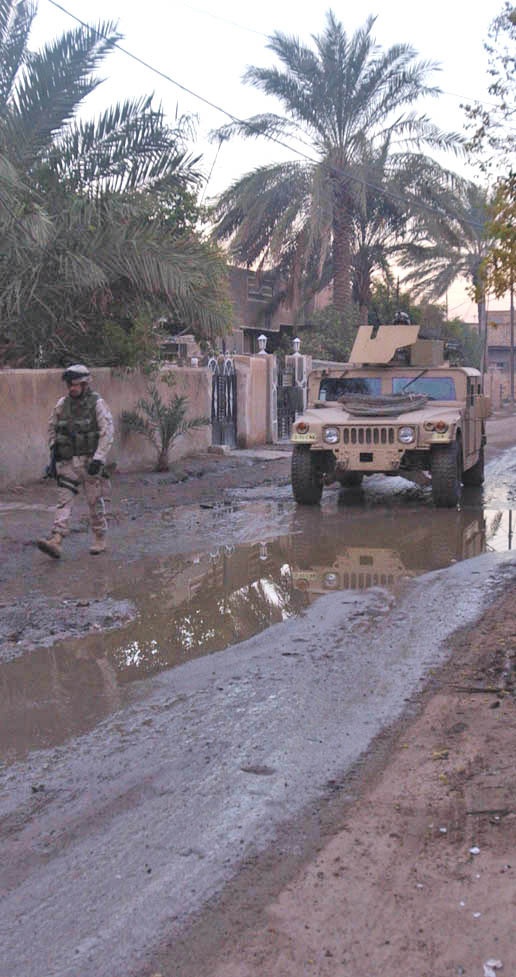 A Soldier walks alongside a Humvee