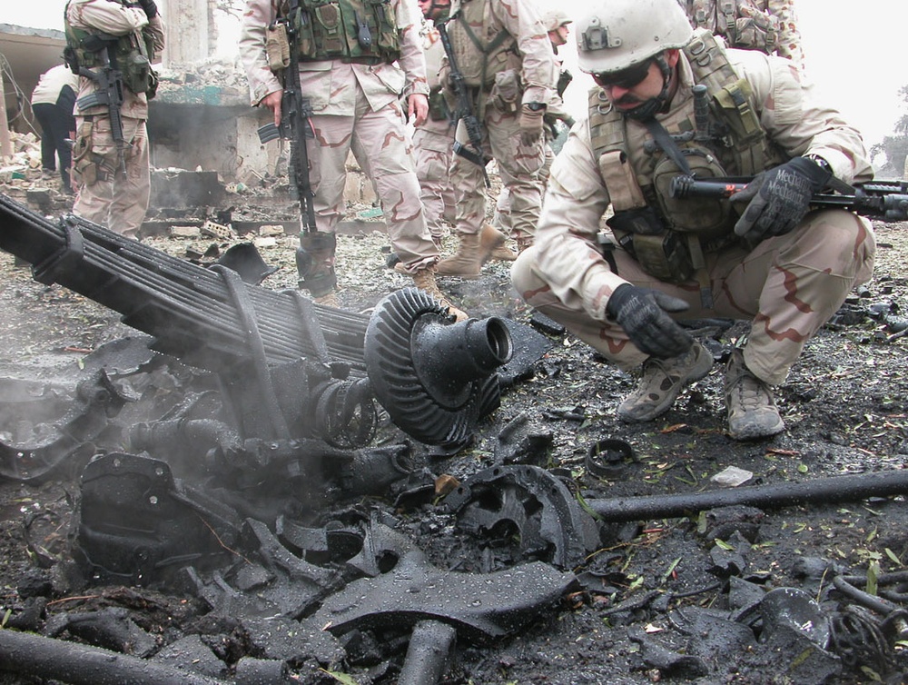 Explosive ordnance personnel examine debris in the crater