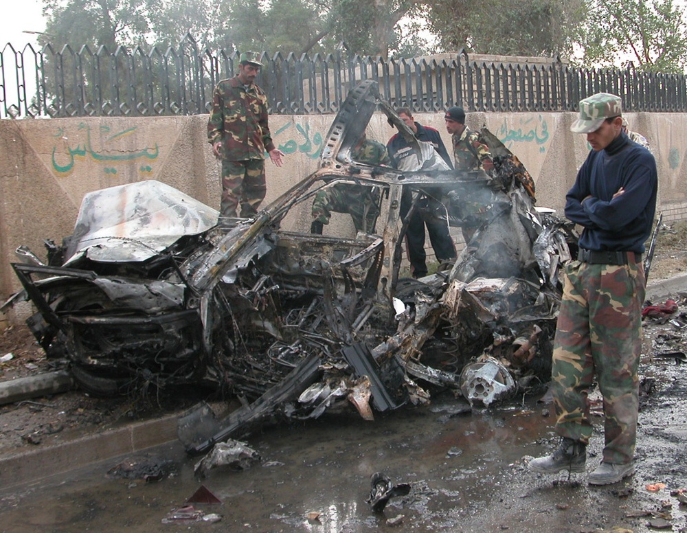 Iraqi Soldiers gather around a car that was destroyed