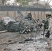 A Soldier looks at the remains of a car