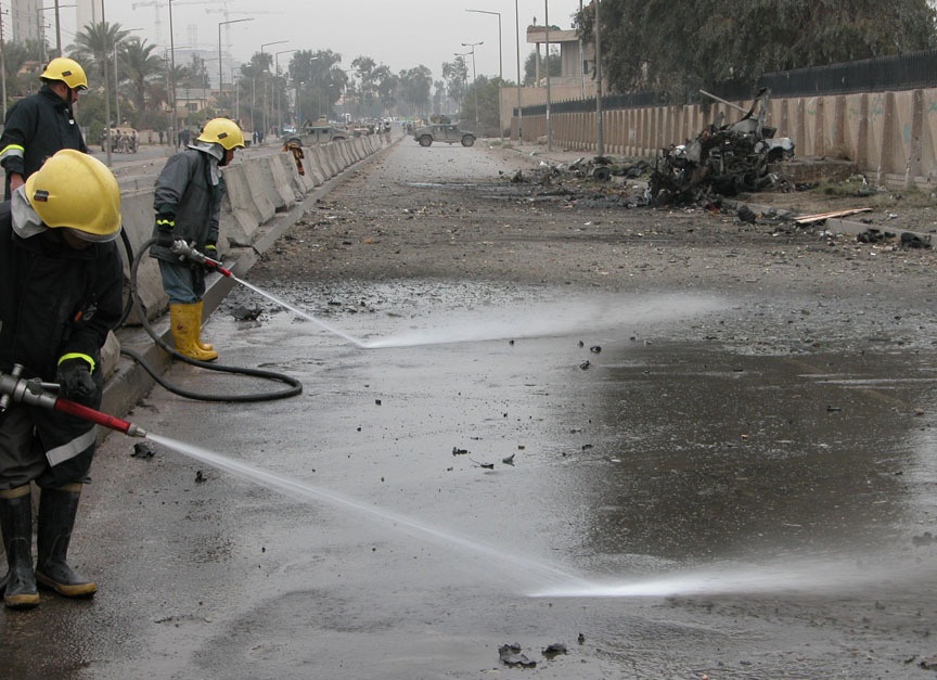 Baghdad firemen spray debris from the road