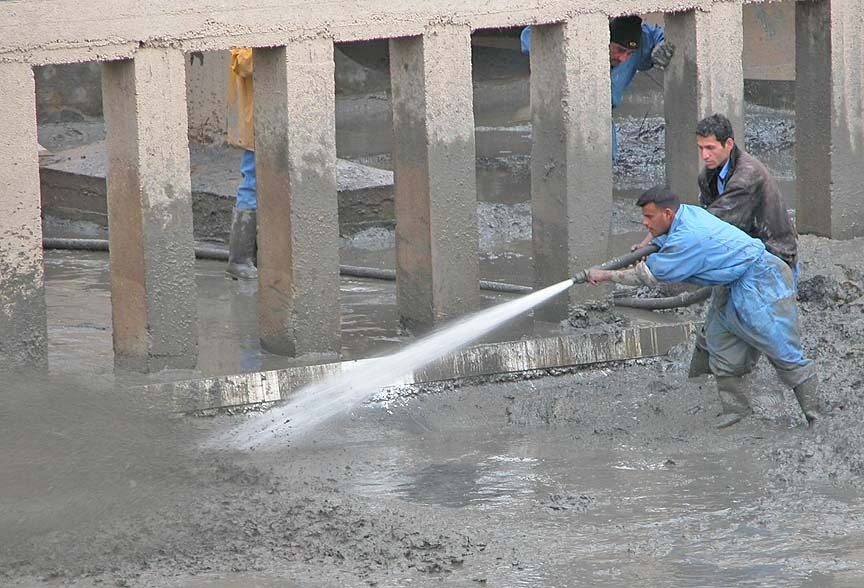 Two Iraqi workers struggle with a water hose