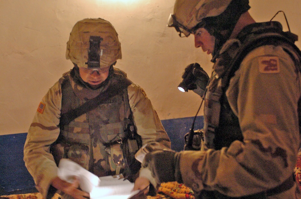 Soldiers inspect paperwork found in a house raided