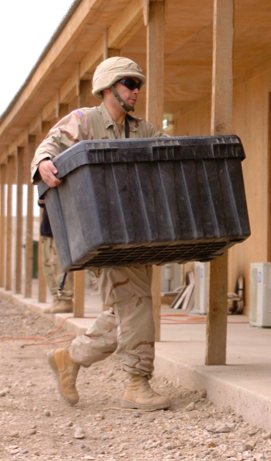 Pfc. Luis Flynn carries a box of office supplies