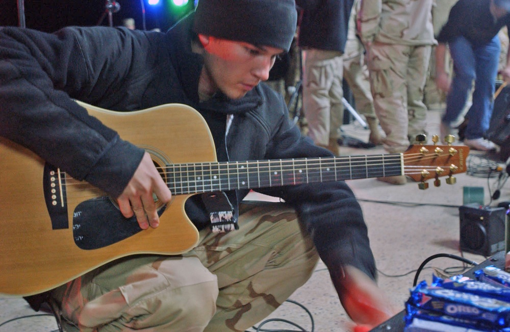 Spc. Christopher Lowry tunes up an acoustic guitar