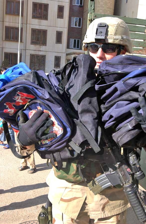 1st Sgt. Guden is almost hidden behind a stack of book bags