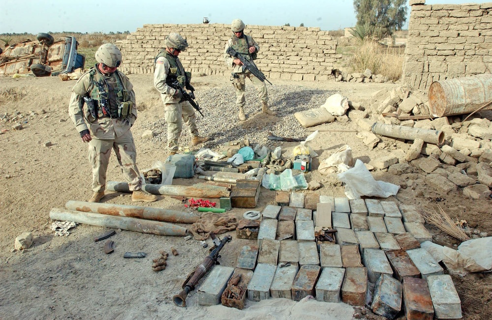 Soldiers inspect a weapons cache found during cordon