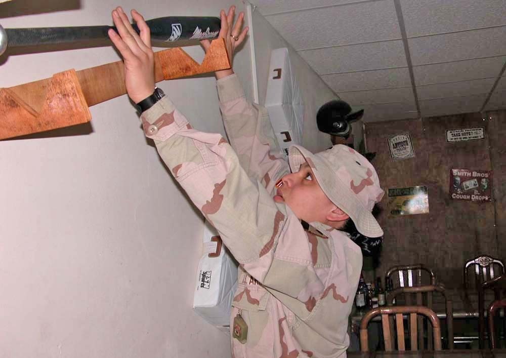 Spc. Ariana Vargas places a baseball bat back on its holder
