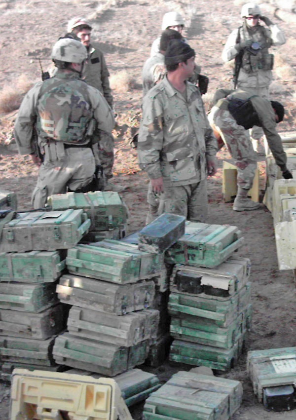 Soldiers stand amidst thousands of small arms ammunition