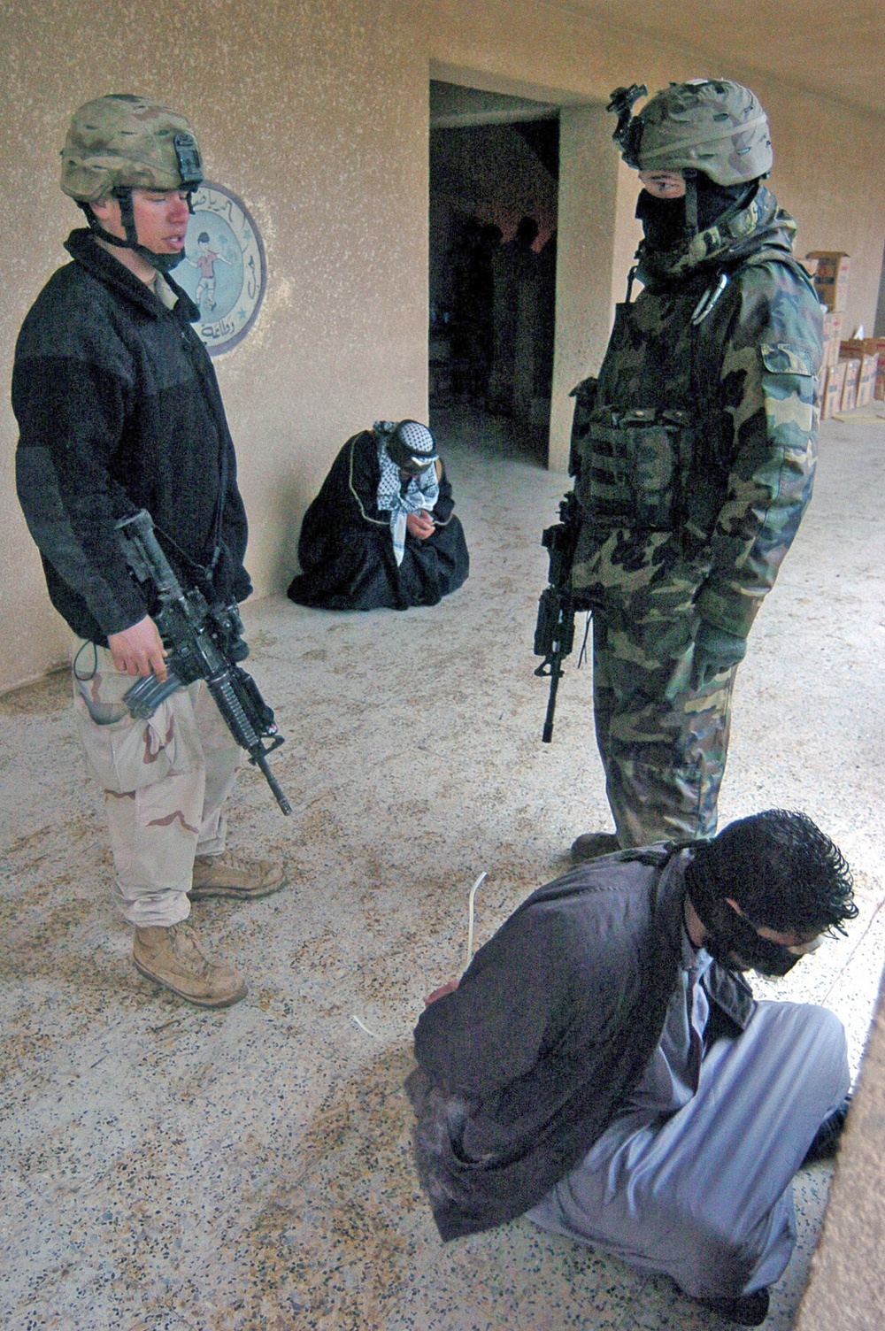 Soldiers guard two detainees at their patrol base