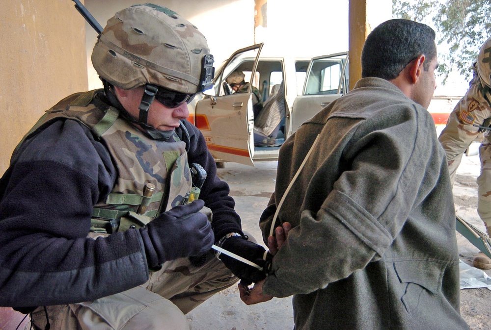 Spc. Mark Gunthrope places flexi-cuffs onto a suspect