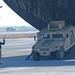 An Airman ground guides a HMMWV off  a C-17