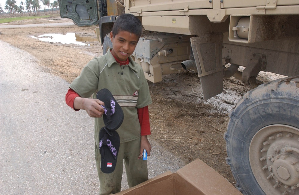 An Iraqi boy picks out a pair of flip flops