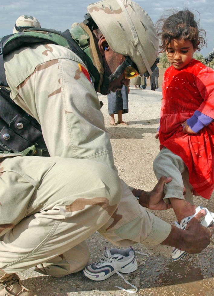 Capt. James helps an Iraqi girl try on a new pair of shoes