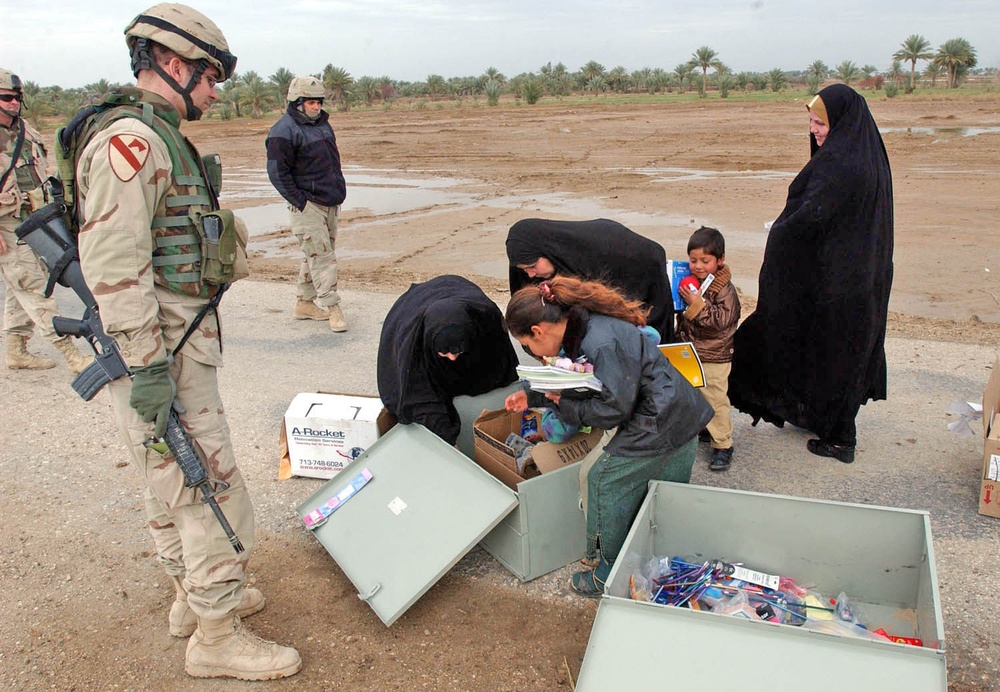 Capt. Ryan Mitcha watches as Iraqi mothers choose school supplie