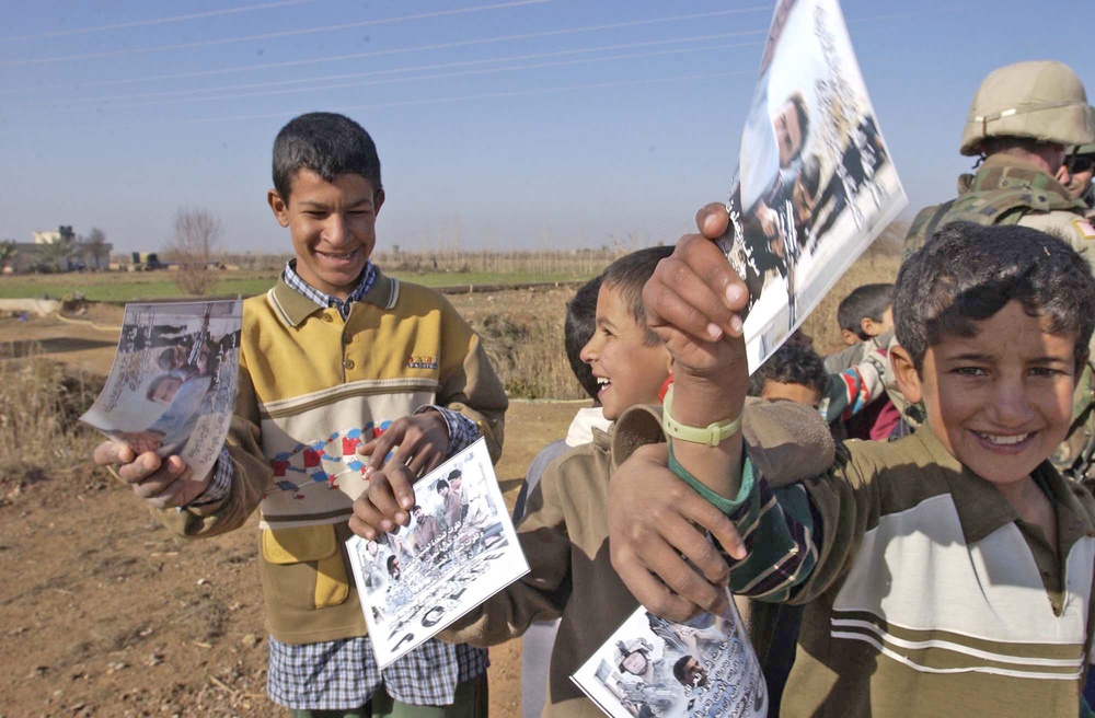 Iraqi children hold up flyers about the upcoming Iraqi elections