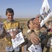 Iraqi children hold up flyers about the upcoming Iraqi elections