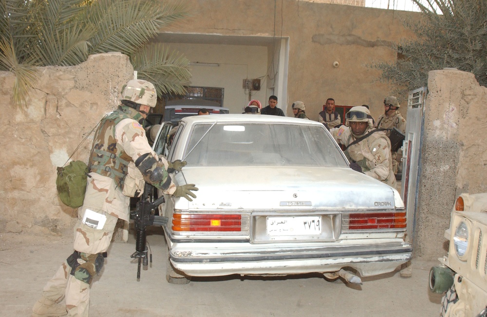 Soldiers push a broken down vehicle out of the yard
