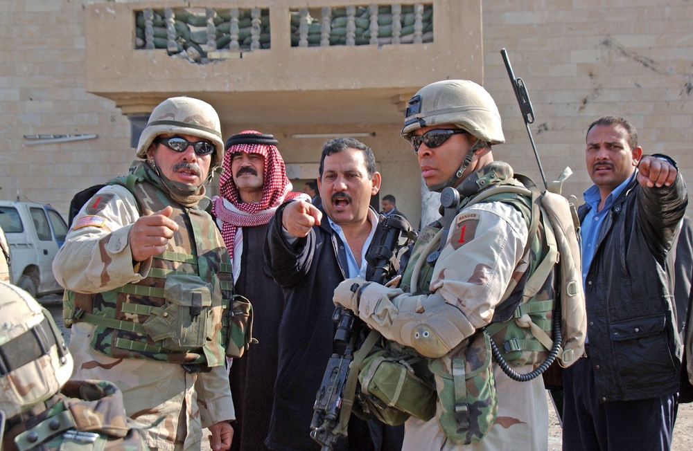 Two Iraqi policeman give a report to Capt. Byard
