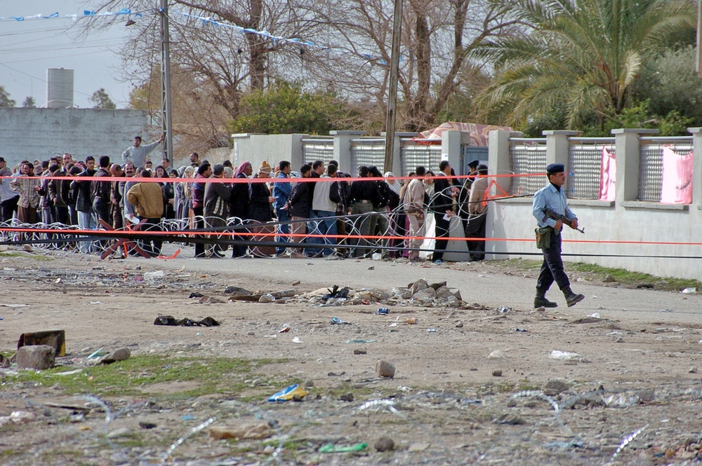An Iraqi Police officer (right) guards a polling site