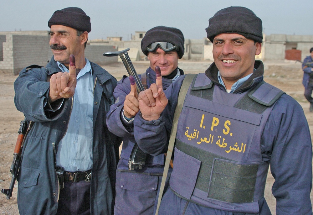 Iraqi Police officers proudly display their ink-covered finger