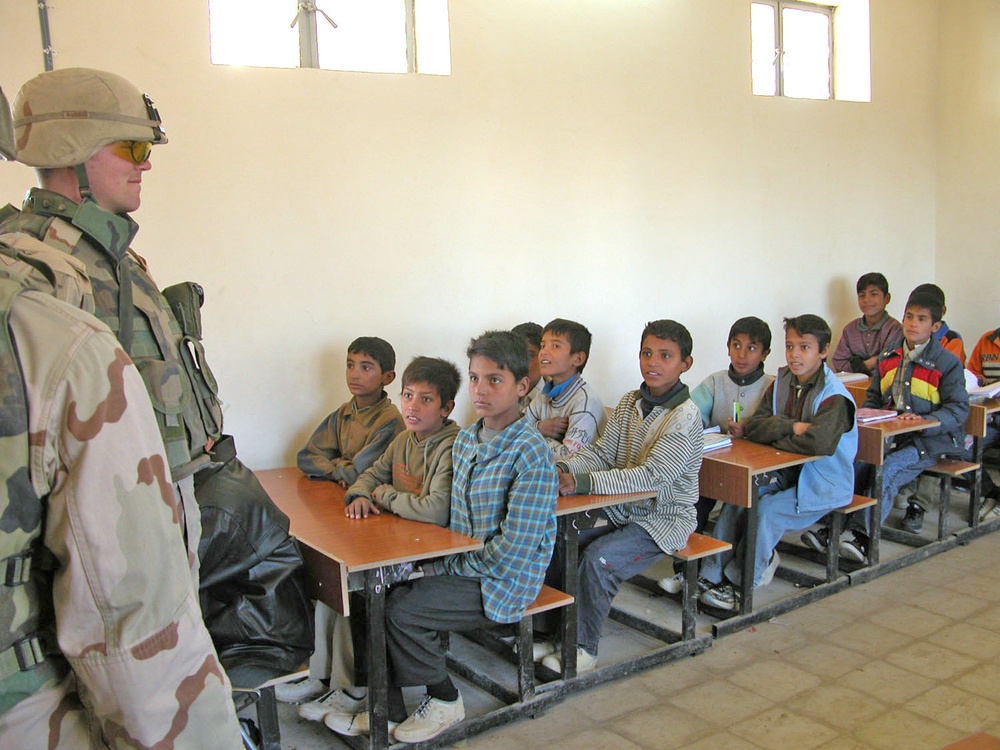 A soldier visits with some students of a school