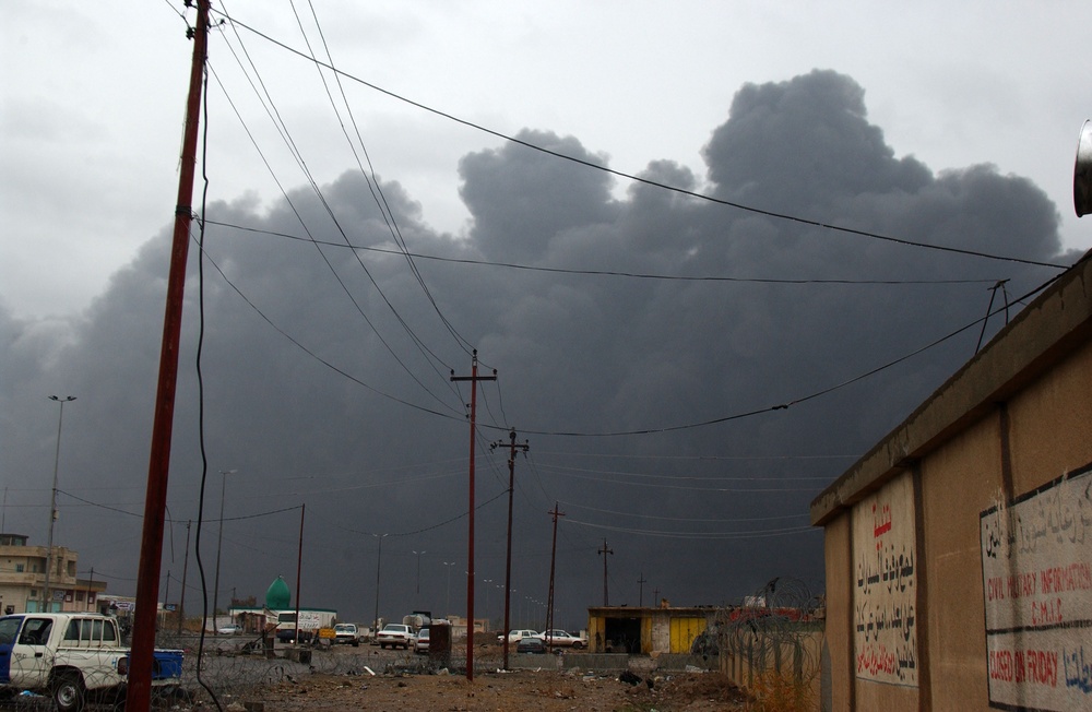 Smoke from an oil and brush fire darkens the sky