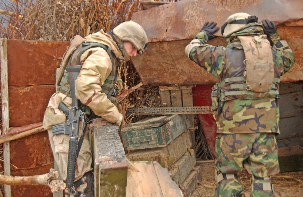 Two soldiers search ammunition boxes found