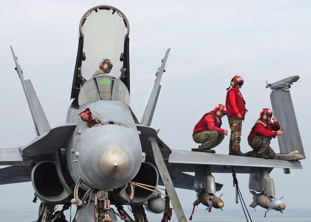 Sailors perform routine maintenance to an F/A-18 Hornet