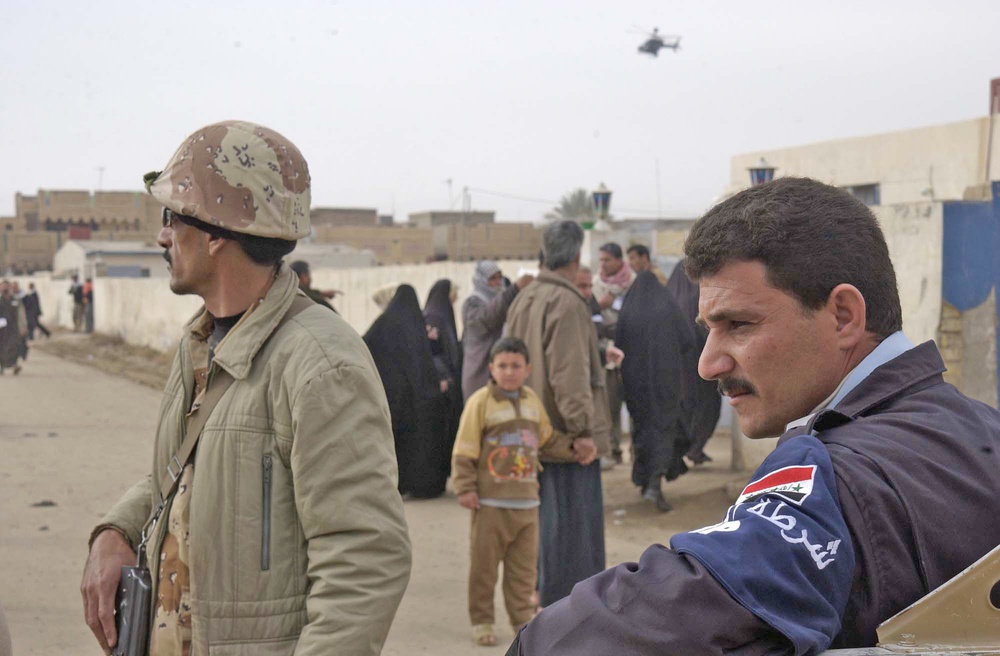 An Iraqi policeman and an Iraqi Army soldier stand guard