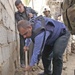 An Iraqi Policeman tries to dig up a mortar that hit a wall