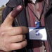 An Iraqi polling center worker holds up his index finger