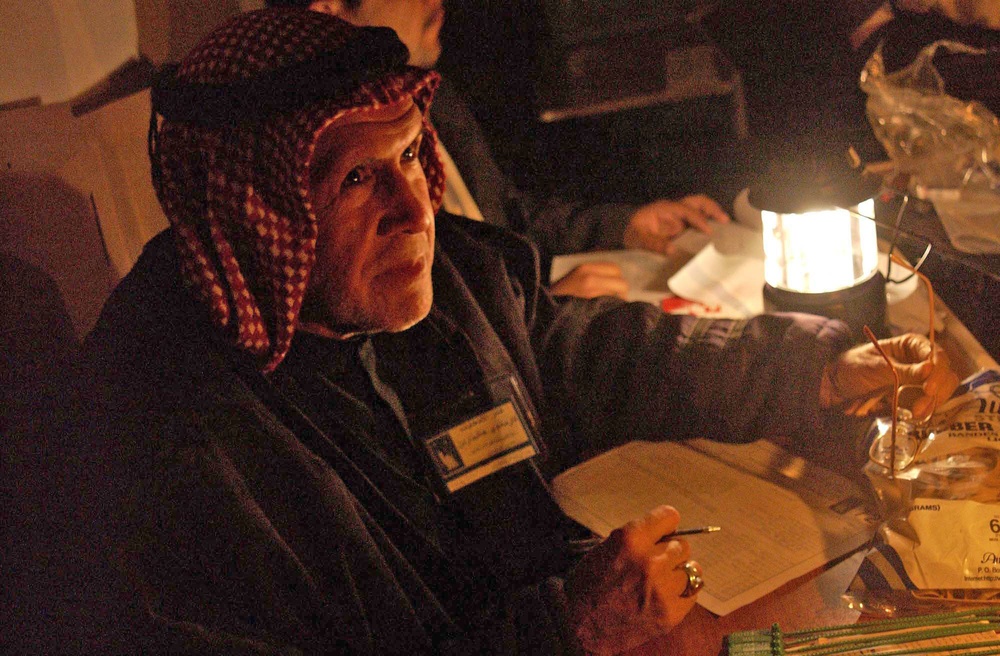 An Iraqi polling center worker goes through the last ballots
