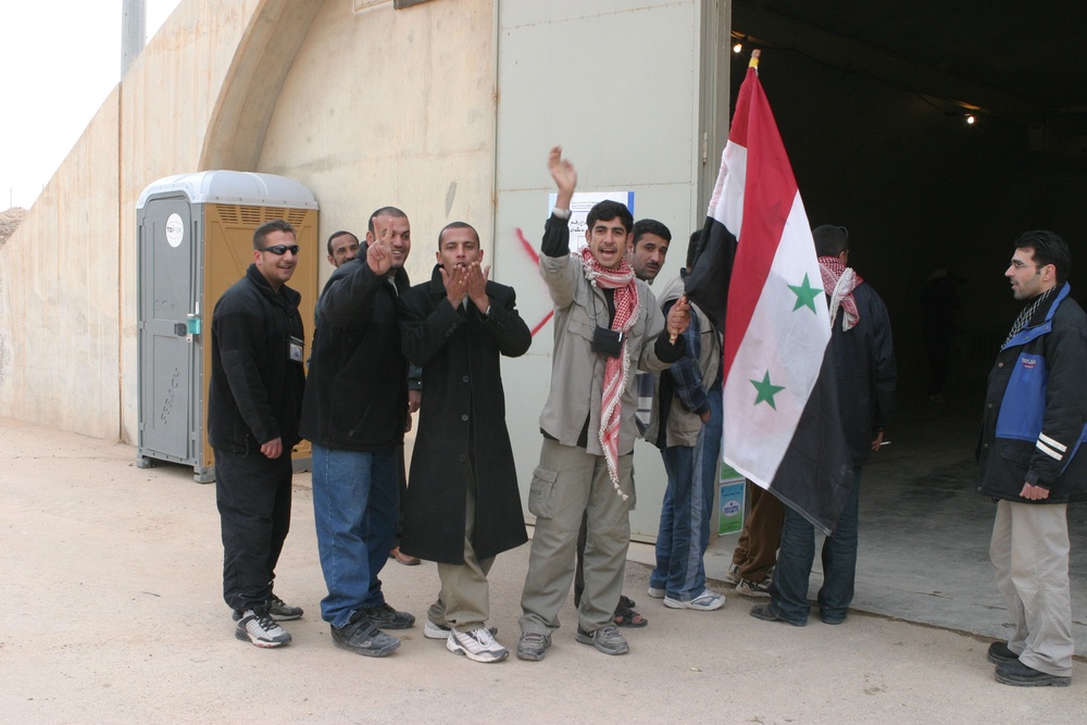 Iraqi citizens line up outside the polling station