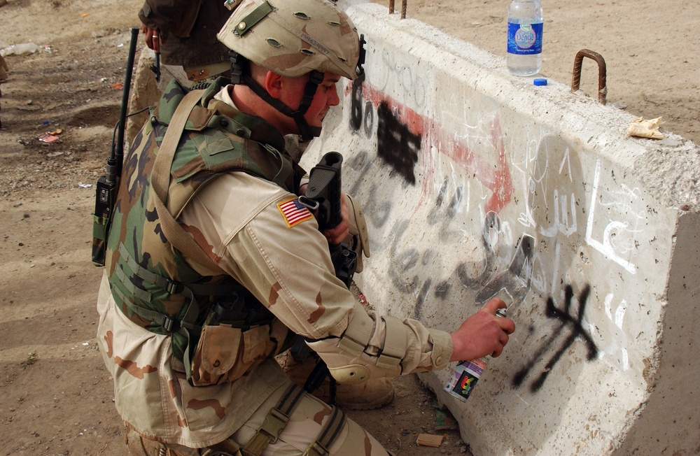 Sgt. Seybold spray- paints over an anti-USA slogan