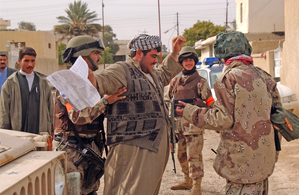 Iraqi National Guardsmen search a voter