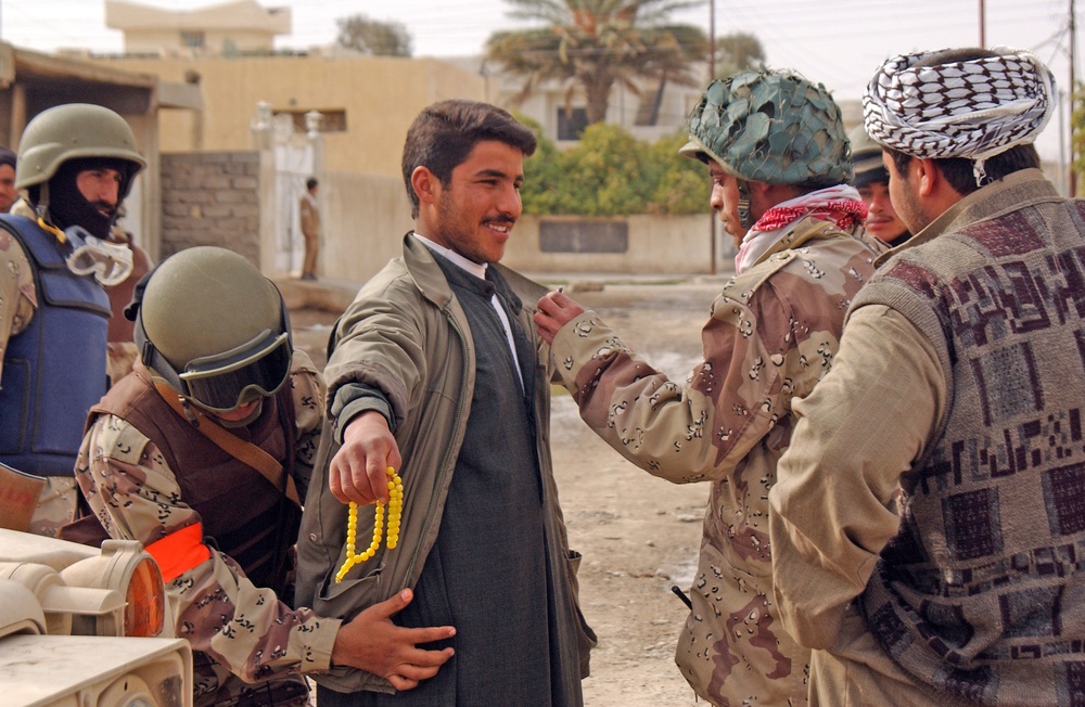 Iraqi National Guardsmen search a voter