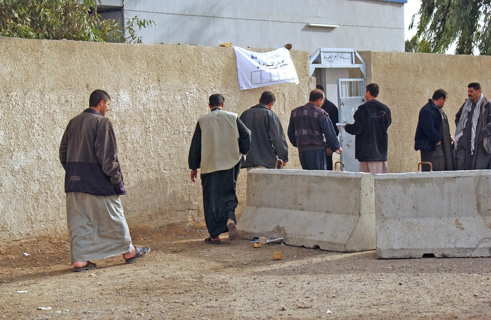 Iraqi voters move into a polling station in a village