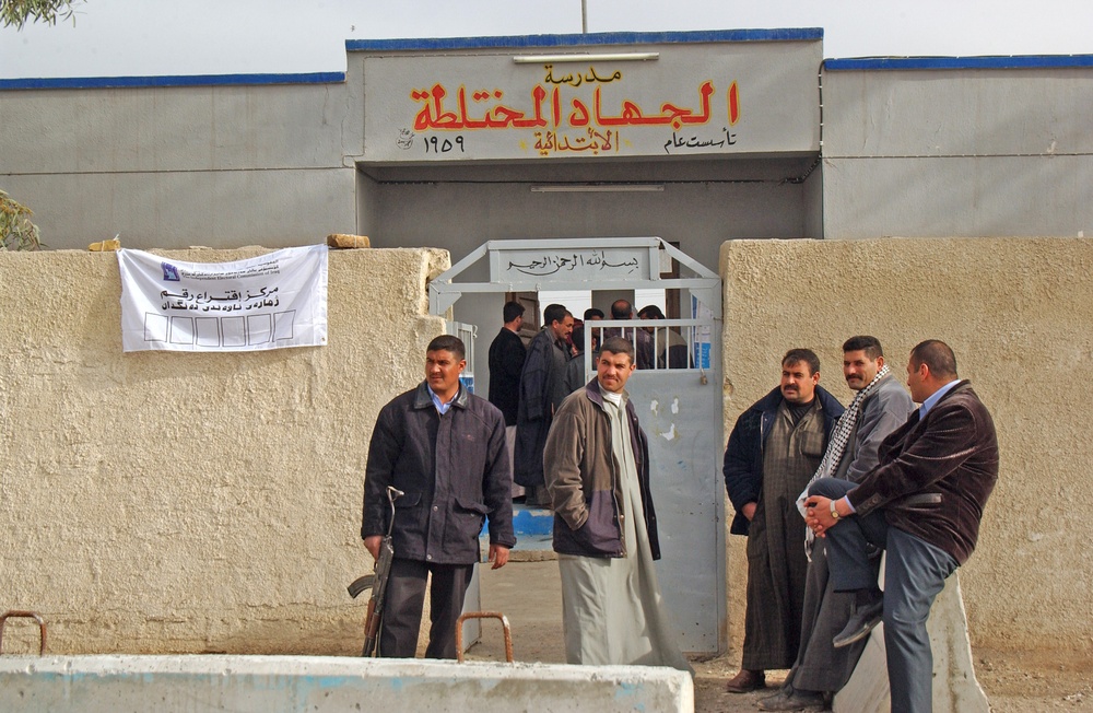 Iraqi policemen guard a polling station in a village